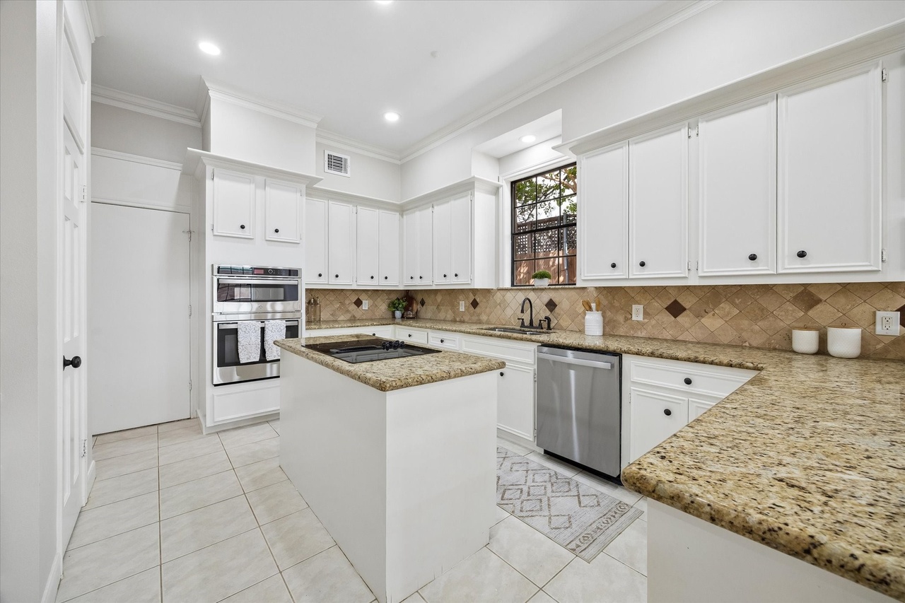 Kitchen with white cabinetry, a center island and built-in appliances